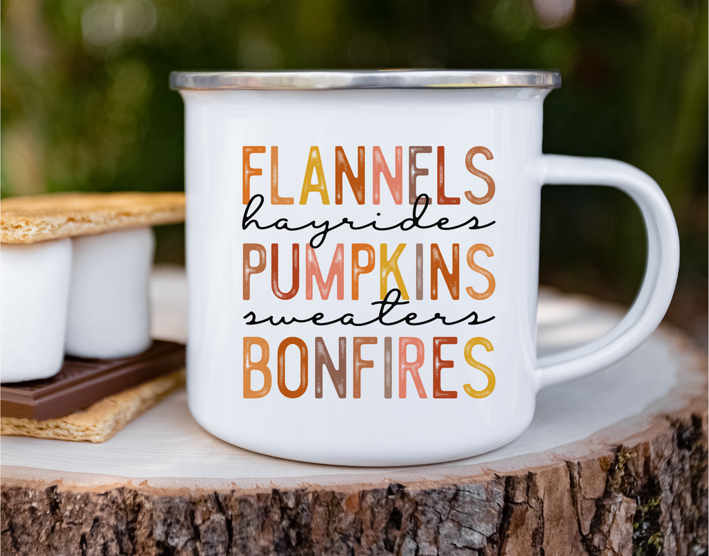 Picture of 12 ounce white enamel camp mug outdoors next to stores, with graphic Flannels, hayrides, pumpkins, sweaters, bonfires. Each letter in muted  fall colors