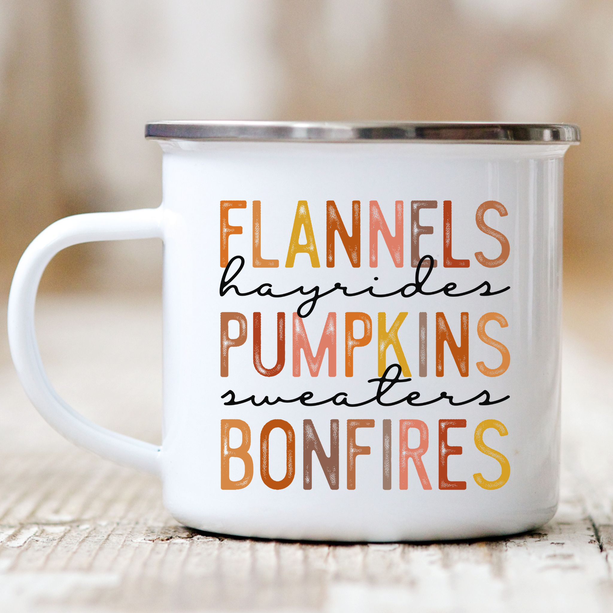 Picture of 12 ounce white enamel camp mug with graphic Flannels, hayrides, pumpkins, sweaters, bonfires. Each letter in muted  fall colors