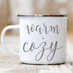 Load image into Gallery viewer, Picture of 11 oz White Enamel Camp Coffee Mug with Silver Rim.  Graphic of Warm and Cozy in Grey colored font.
