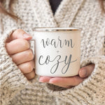 Load image into Gallery viewer, Picture of 11 oz white enamel Camp Coffee Mug with Silver Rim.  Graphic of Warm and Cozy in Grey
